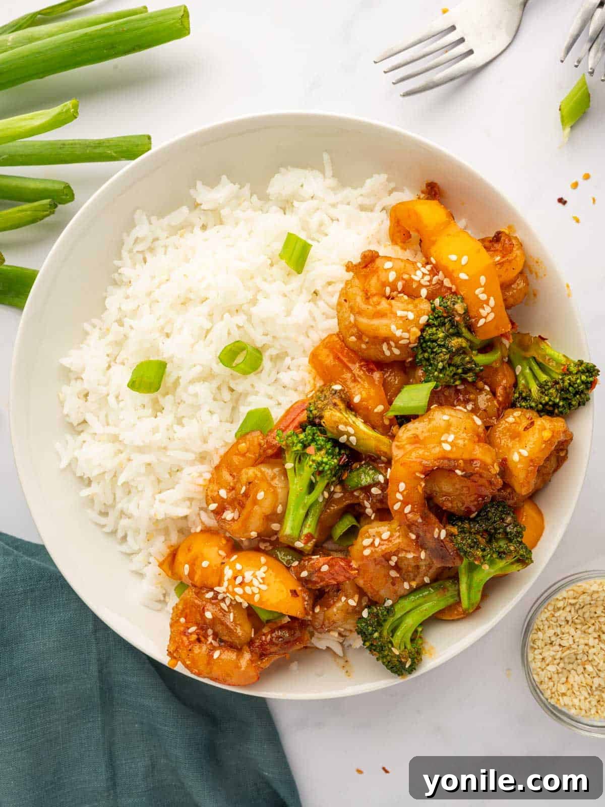 Sticky Sweet Chili Glazed Shrimp 9 A plate of sweet chili shrimp with white rice, garnished with green onions and sesame seeds.