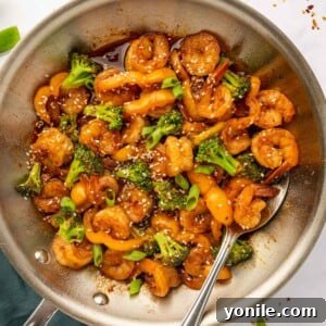 A spoon stirring shrimp in sweet chili sauce, showcasing the rich color and texture.