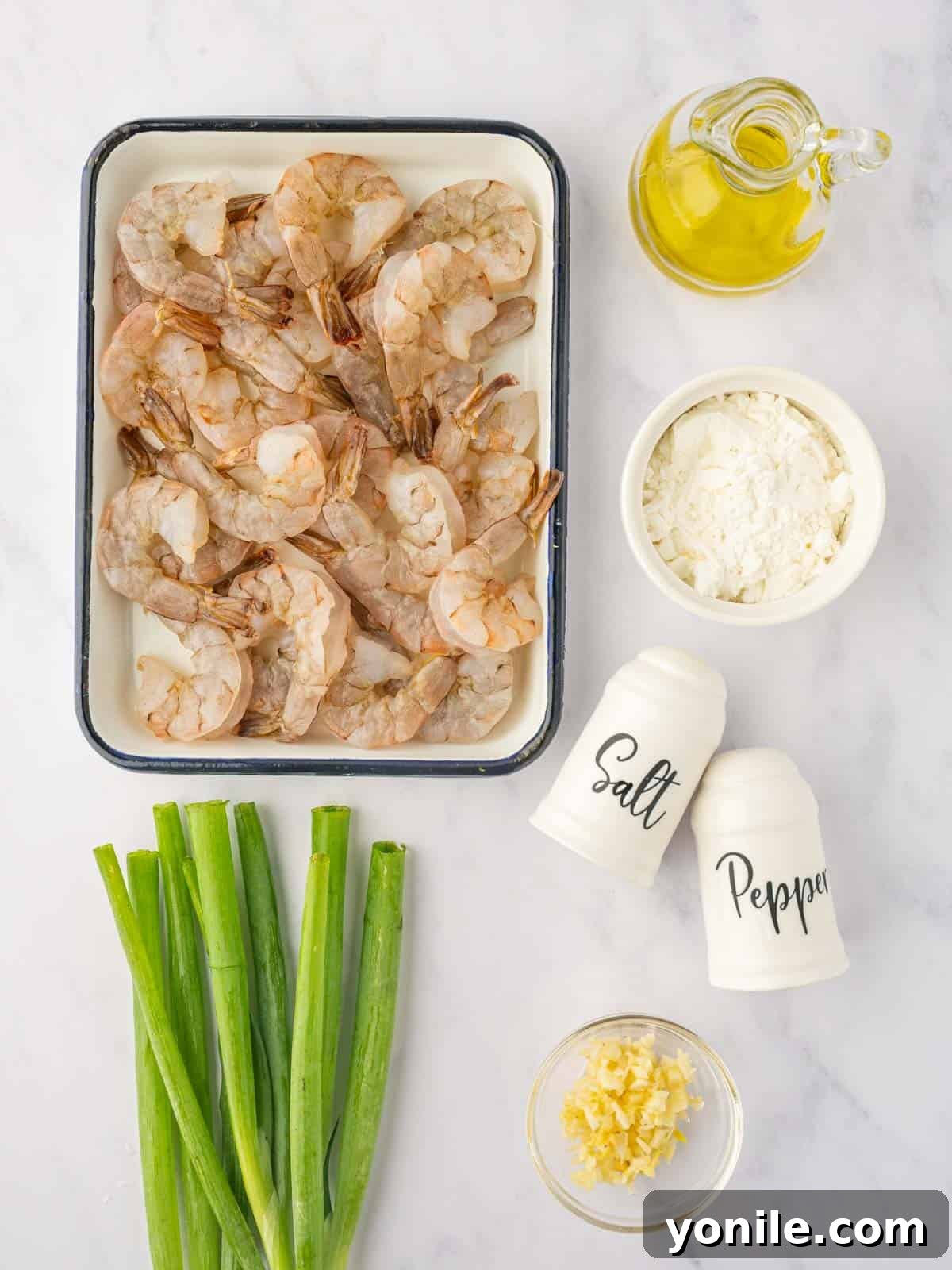 Ingredients for Chinese Salt and Pepper Shrimp laid out on a wooden board: large shrimp, cornstarch, salt, pepper, garlic, and green onions.
