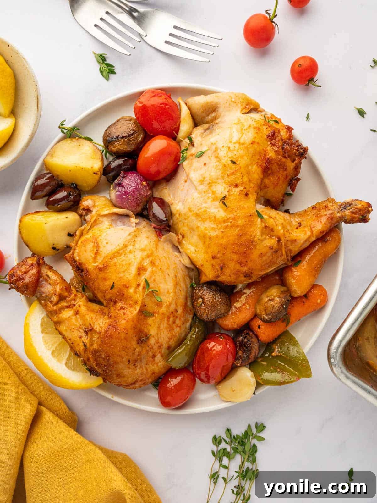 Plated roasted chicken quarters with a colorful medley of Mediterranean vegetables, ready to be enjoyed.