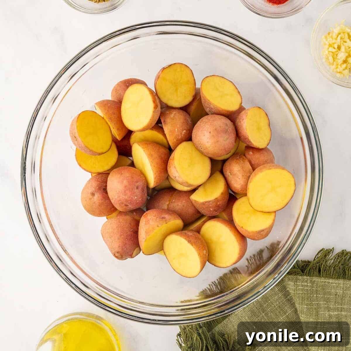 Red potatoes are meticulously cut in half, showcasing their uniform size and readiness for seasoning.