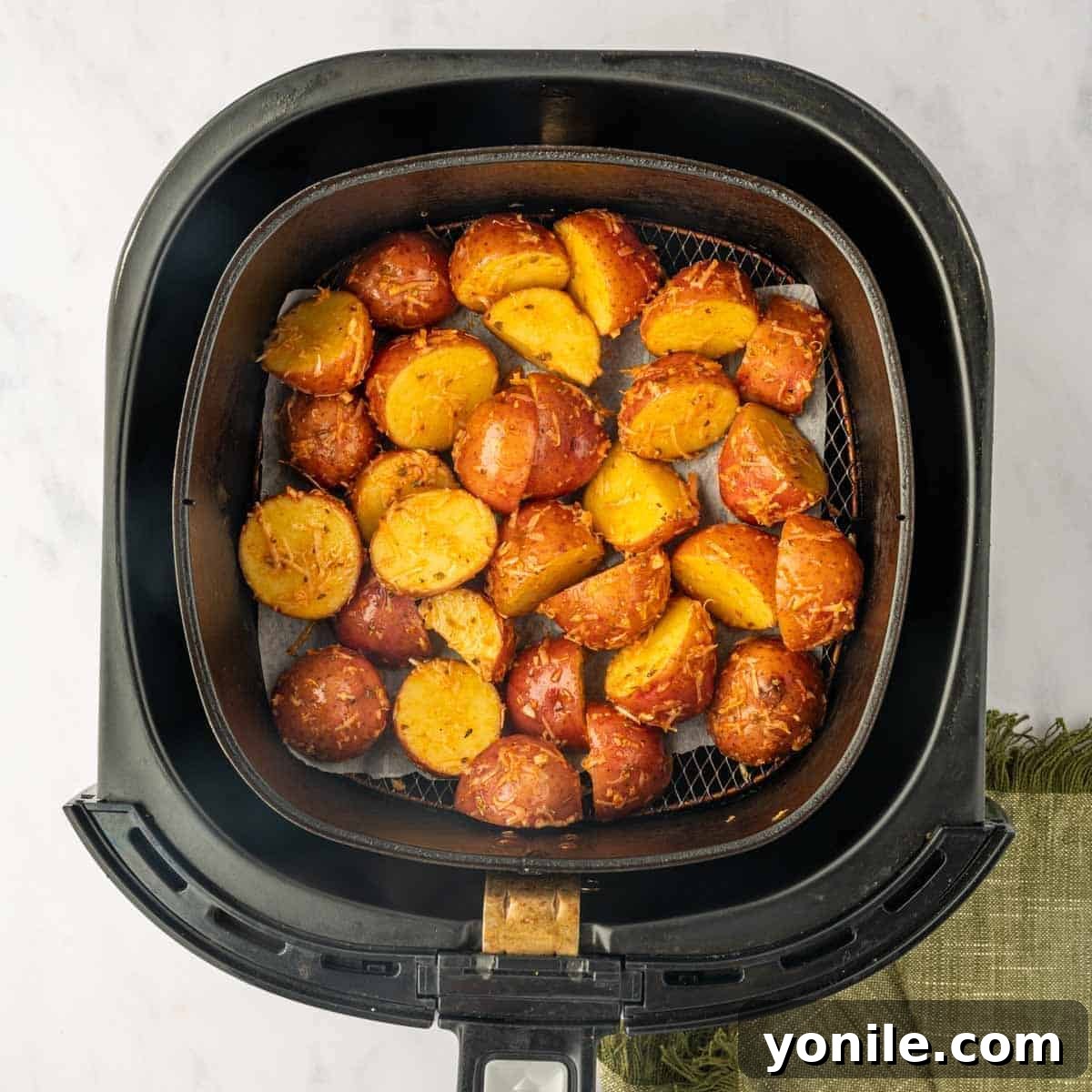 Crispy, golden-brown red potatoes are perfectly arranged in a single layer within an air fryer basket, ready to be served.