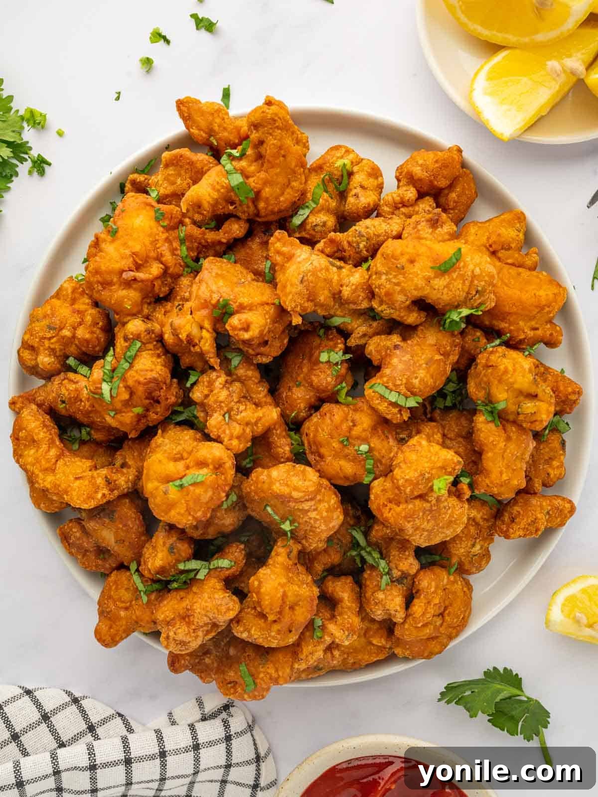 A large serving platter of chicken pakora, garnished with fresh cilantro and lemon wedges.