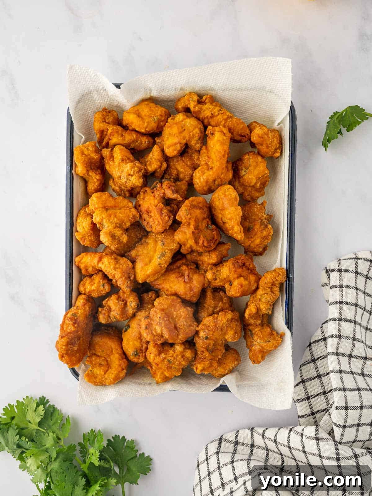 Crispy fried chicken pakora bites resting on paper towels to drain excess oil after frying.