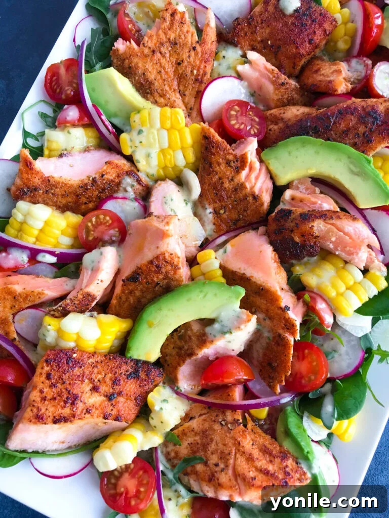 Overhead shot of a vibrant spicy salmon salad on a platter with dressing drizzled over it.