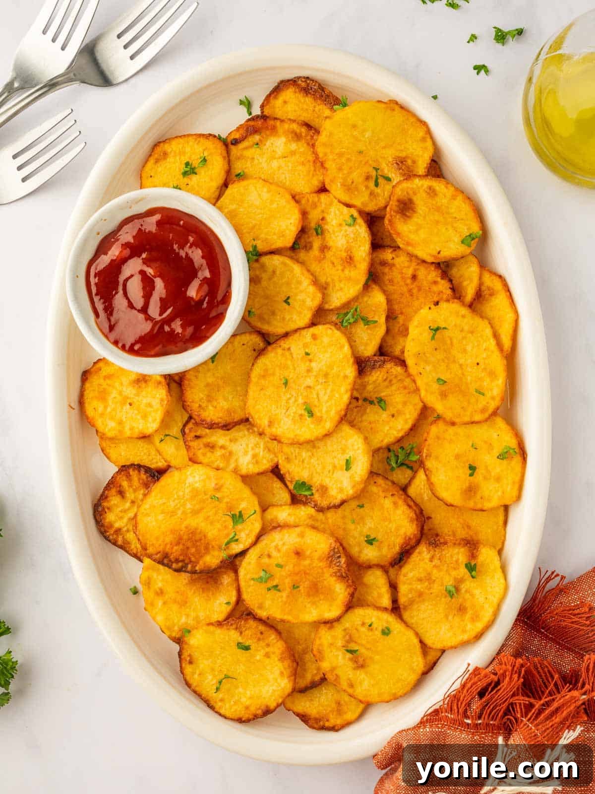 A large platter of crispy air fryer potato chips, with a small dish of ketchup for dipping.