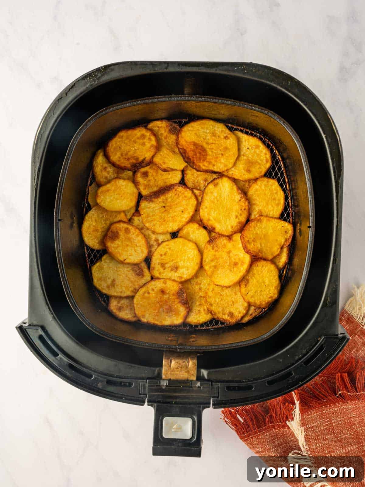 A close-up of golden, crispy potatoes in an air fryer basket after cooking, showcasing their perfect texture.