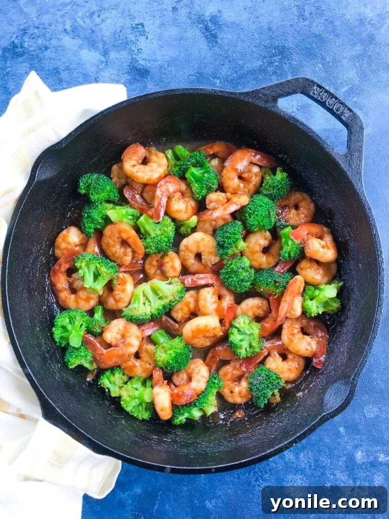 Teriyaki Shrimps cooking in a skillet with broccoli florets