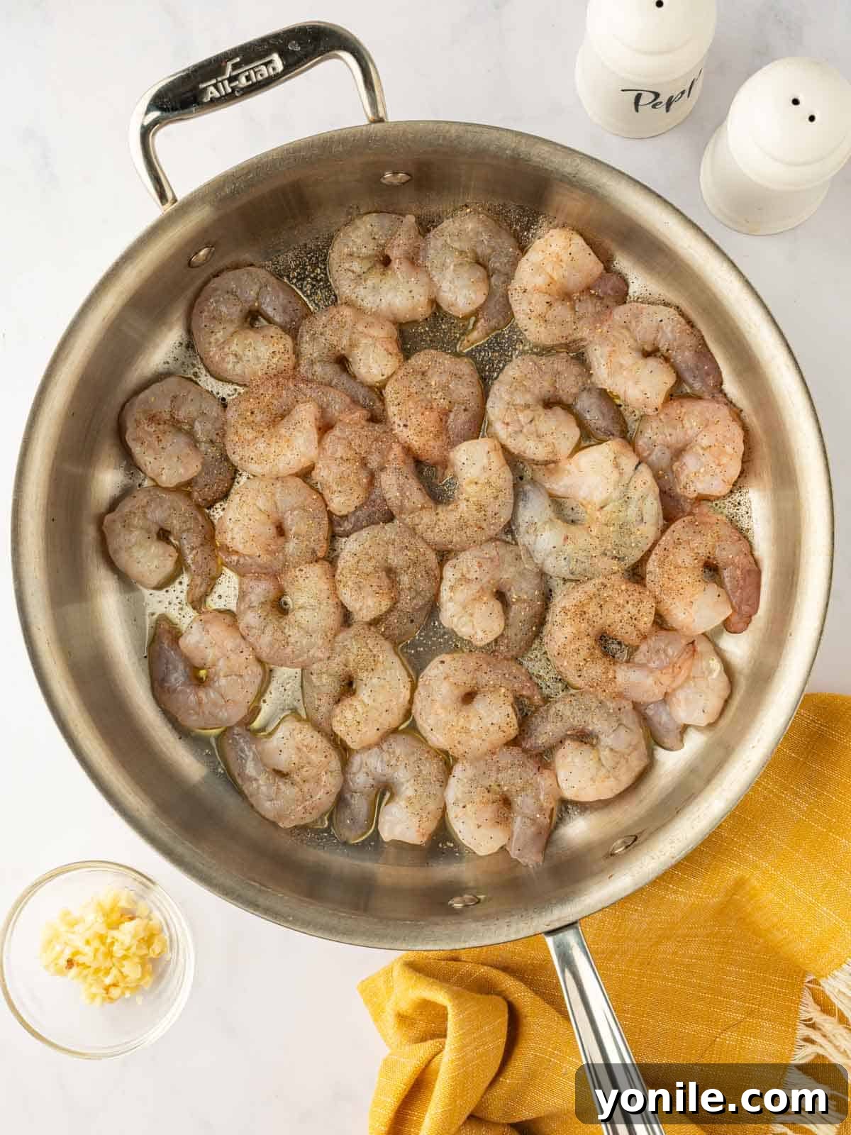 Raw seasoned shrimp in a skillet.