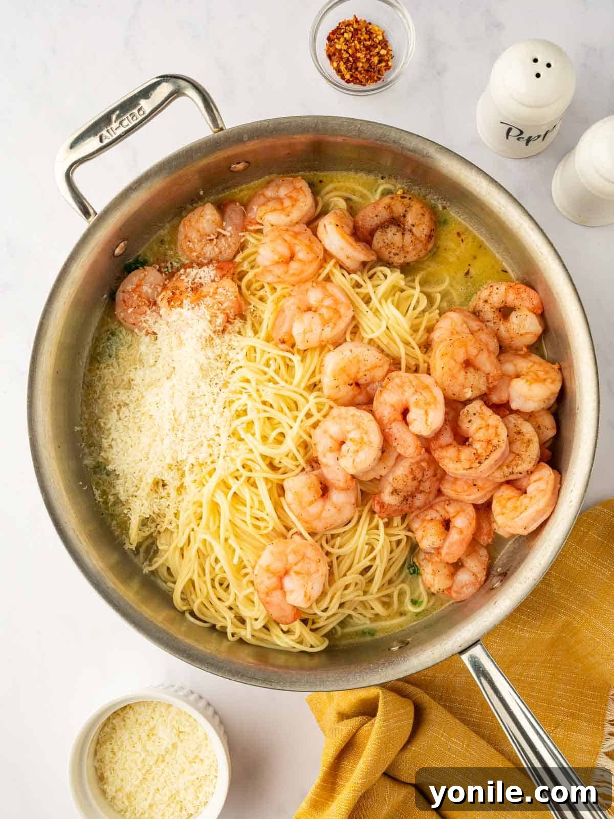 Process of mixing shrimp with pasta and cheese.