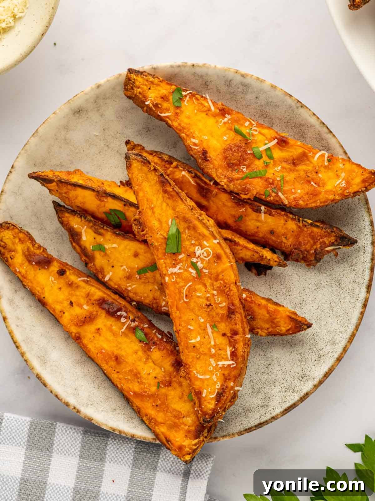 Several perfectly air-fried sweet potato wedges artfully arranged on a clean white plate, ready for an elegant serving presentation.