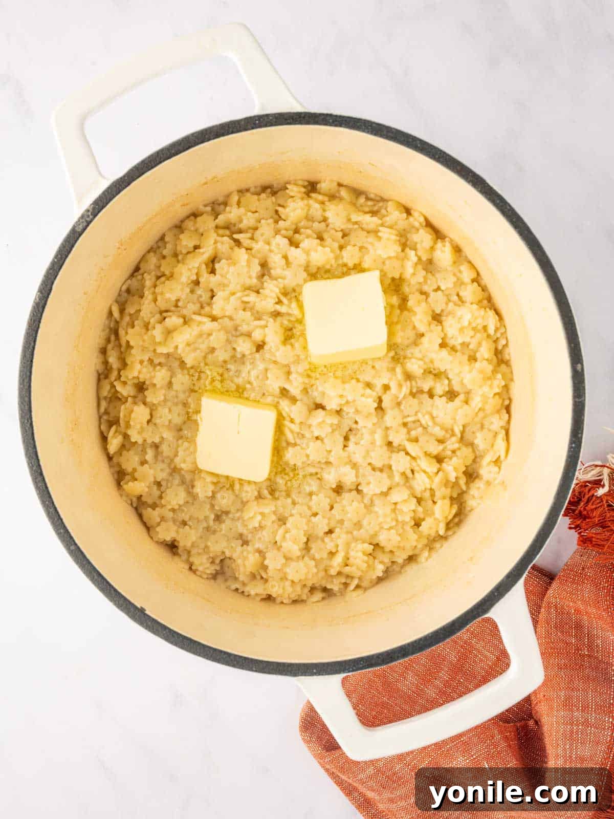 Italian Pastina Comfort 6 Butter melts over a dutch oven filled with cooked pastina pasta noodles.