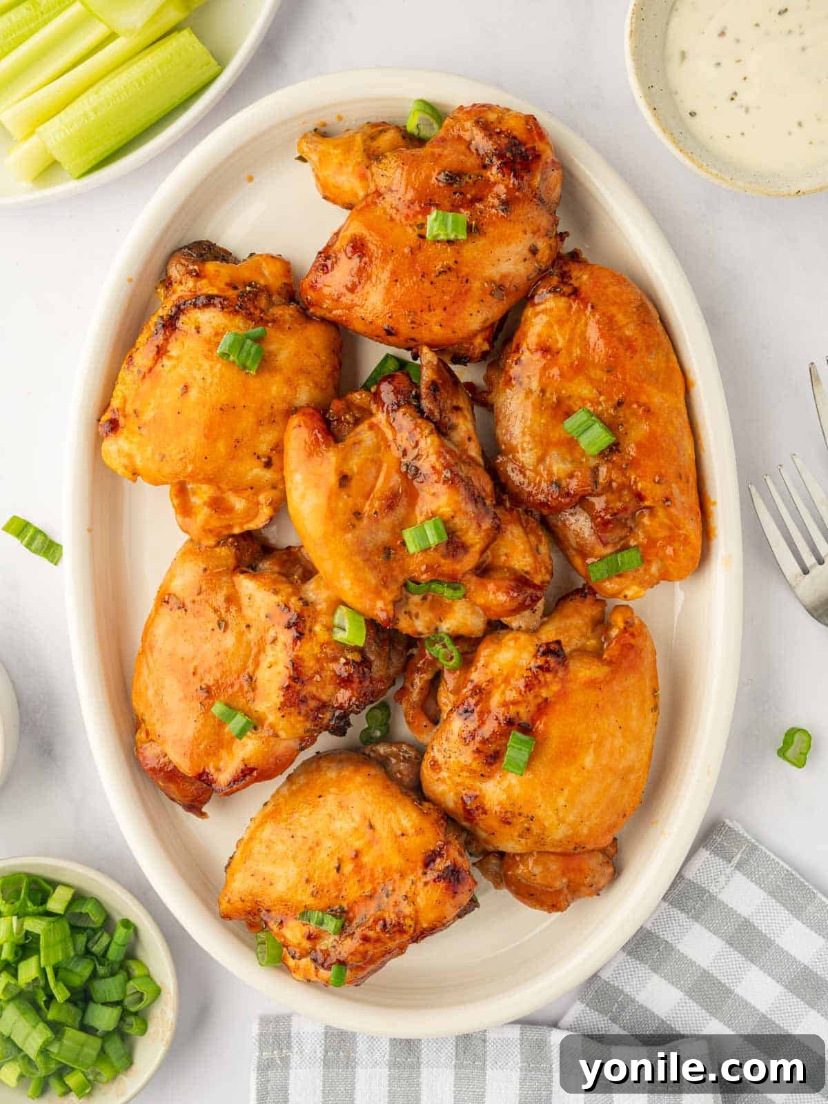 Baked buffalo chicken on a platter, garnished with fresh herbs, ready to serve.