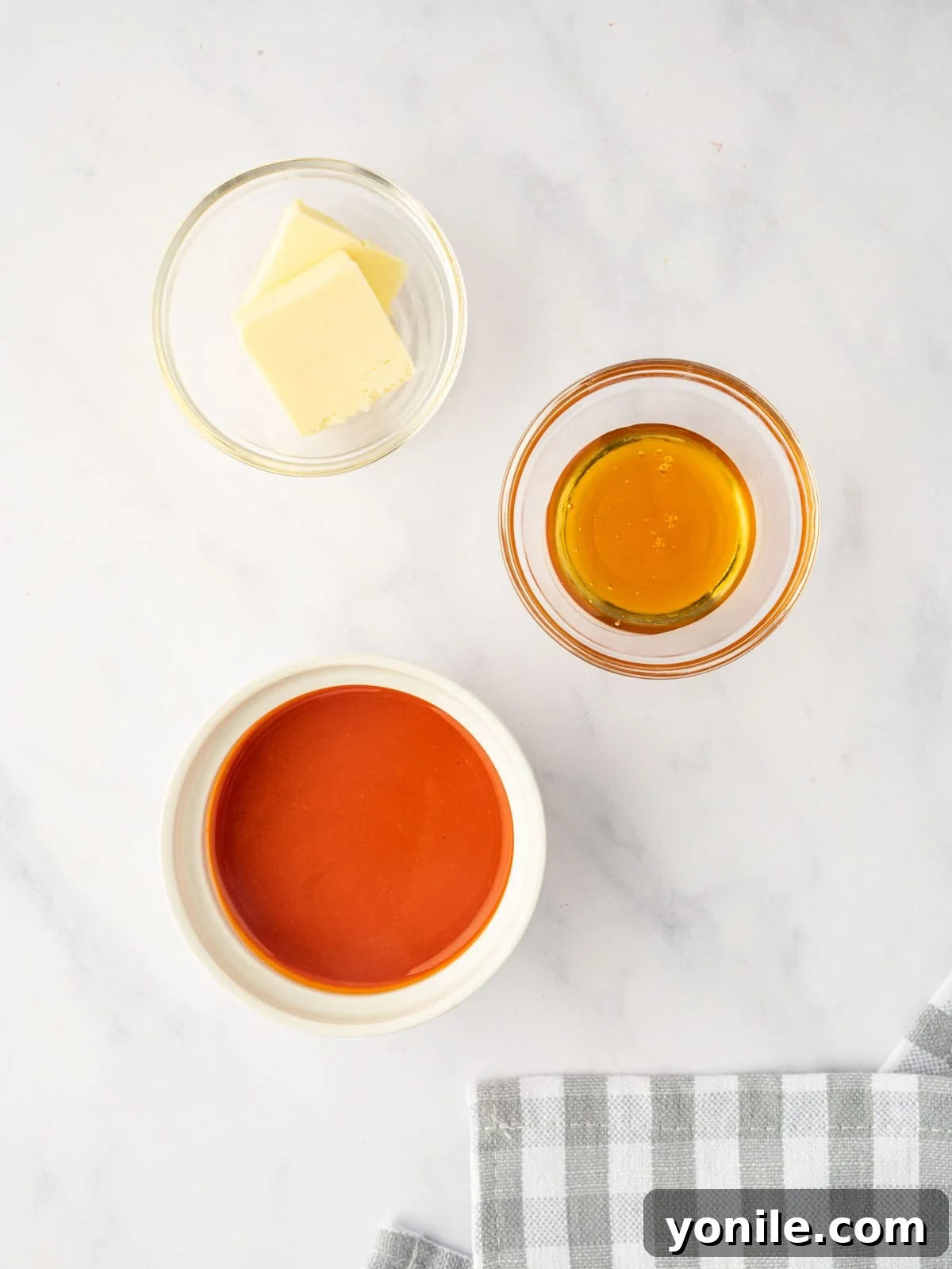 A bowl of hot sauce, melted butter, and honey are displayed, ready to be combined for buffalo sauce.