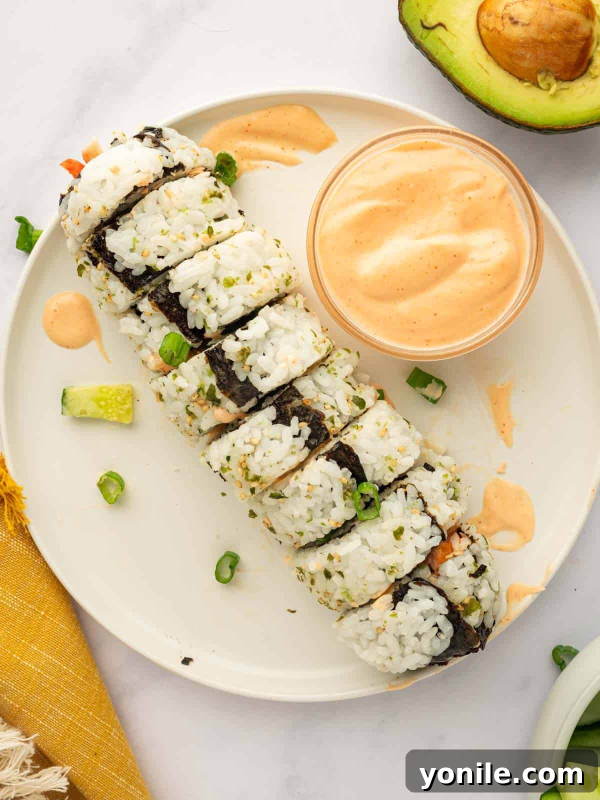 Dynamite Salmon Roll 14 A perfectly sliced roll of spicy salmon sushi is presented on a plate, alongside a dollop of spicy mayo.