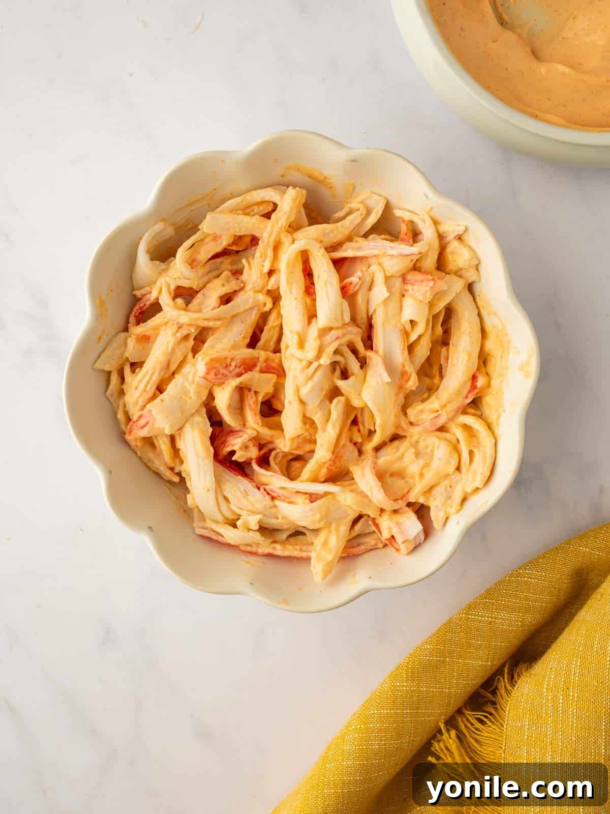 Dynamite Salmon Roll 6 Shredded imitation crab meat is tossed with a creamy spicy mayo sauce in a bowl.