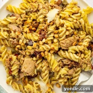 A plate of Tuna Pesto Pasta, garnished with fresh basil, ready to be served.