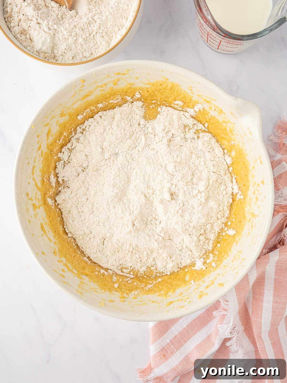 Dry ingredients are gradually combined with wet ingredients to form the cake batter.