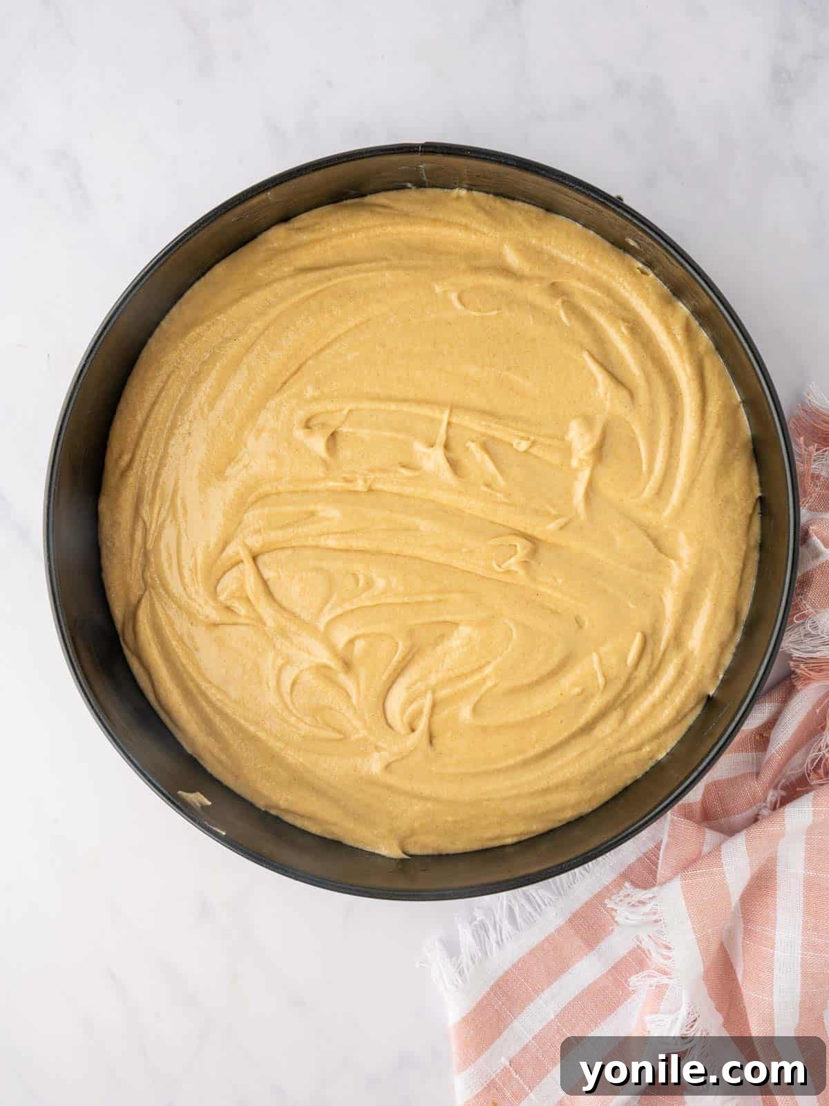 Smooth cake batter is gently poured over the arranged pear layer in the pan.