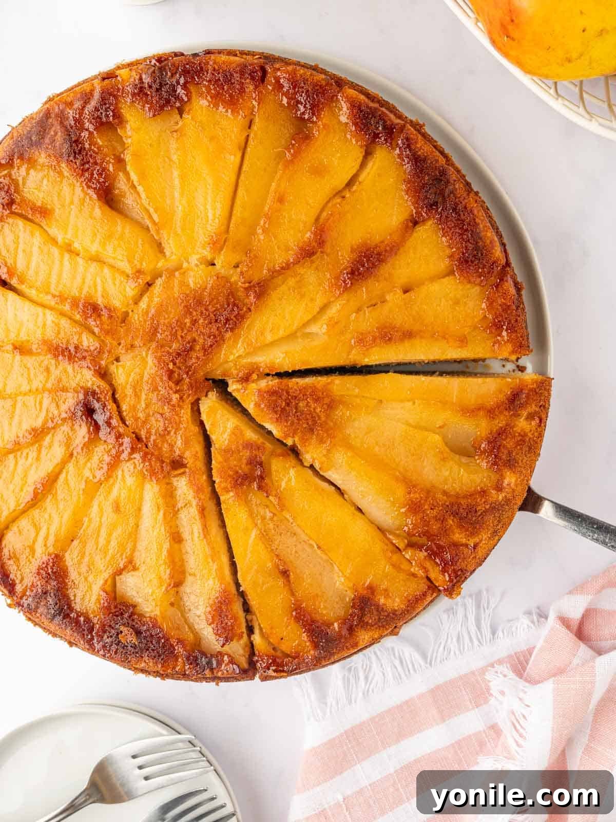 A beautiful slice of pear cake is cut and lifted from the whole cake.