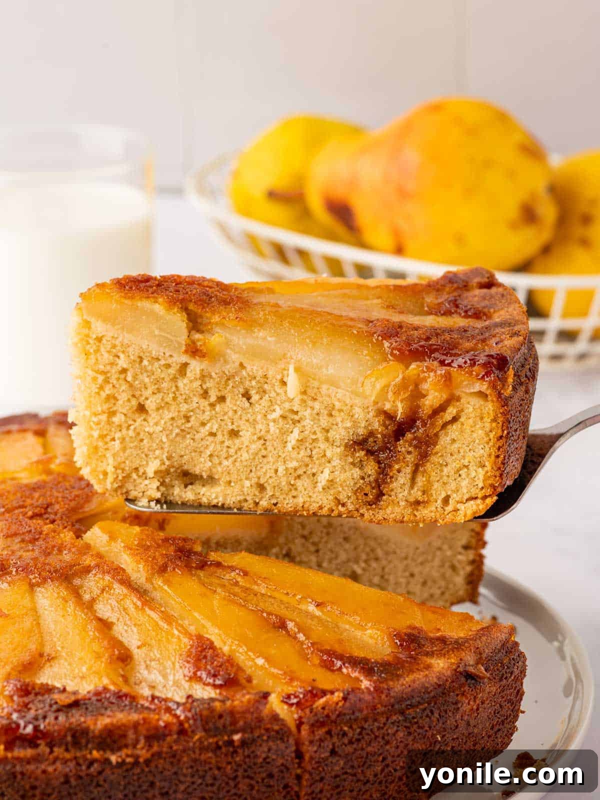 A piece of pear cake is expertly lifted, ready to be served.