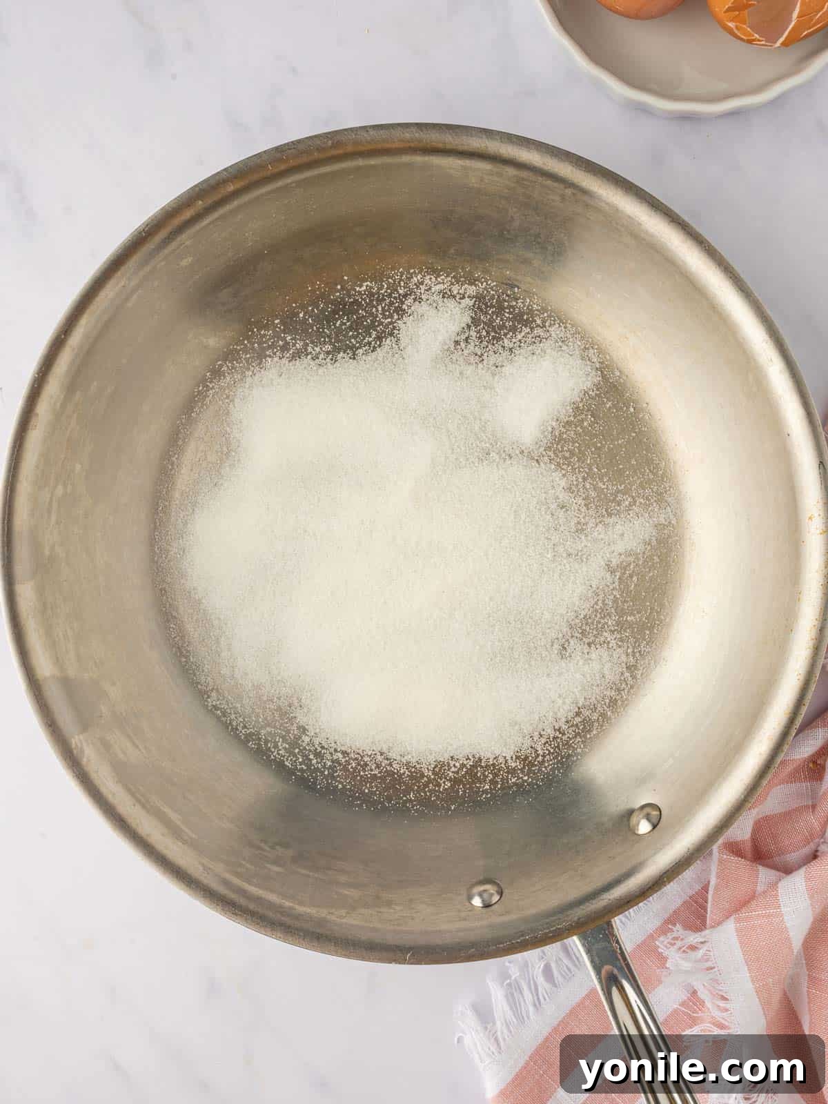 Granulated sugar browning in a skillet to form caramel sauce.