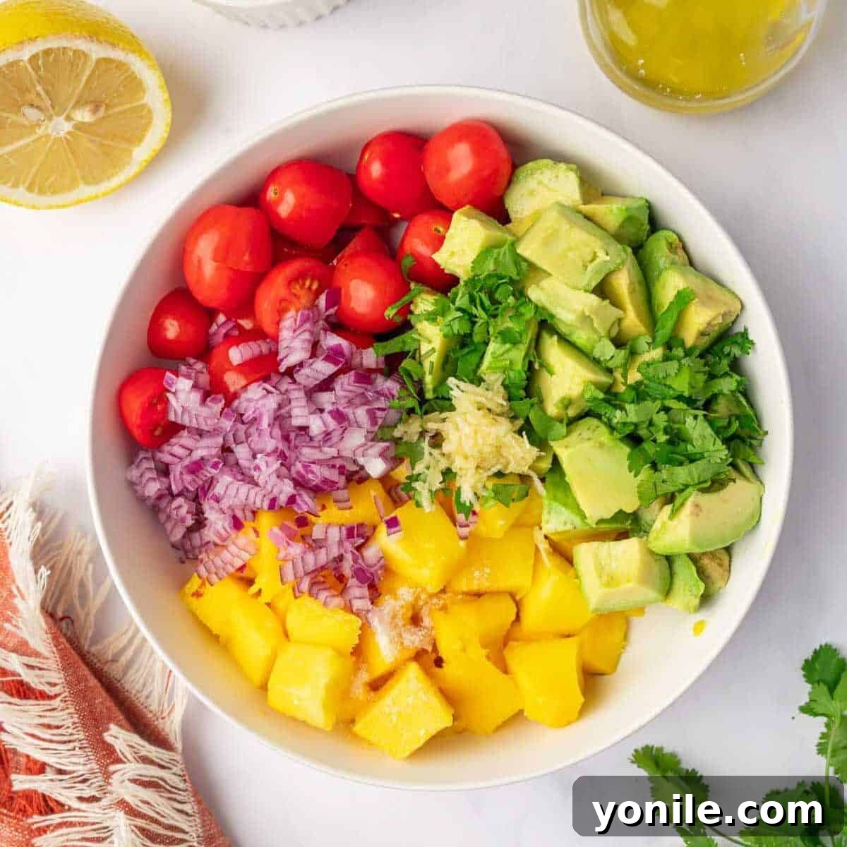 All ingredients of avocado mango salad in a bowl.
