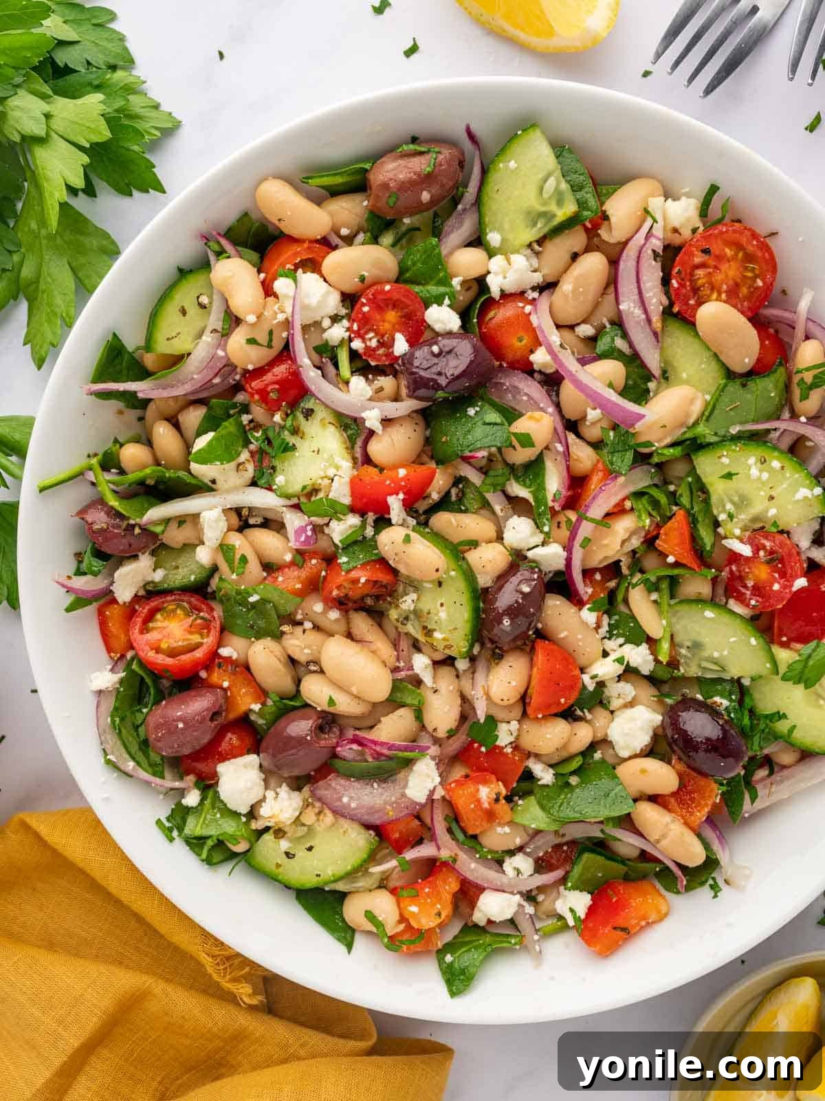 A large bowl of Mediterranean salad with beans and veggies. The finished Greek white bean salad, beautifully presented in a large serving bowl, showcasing its colorful ingredients.