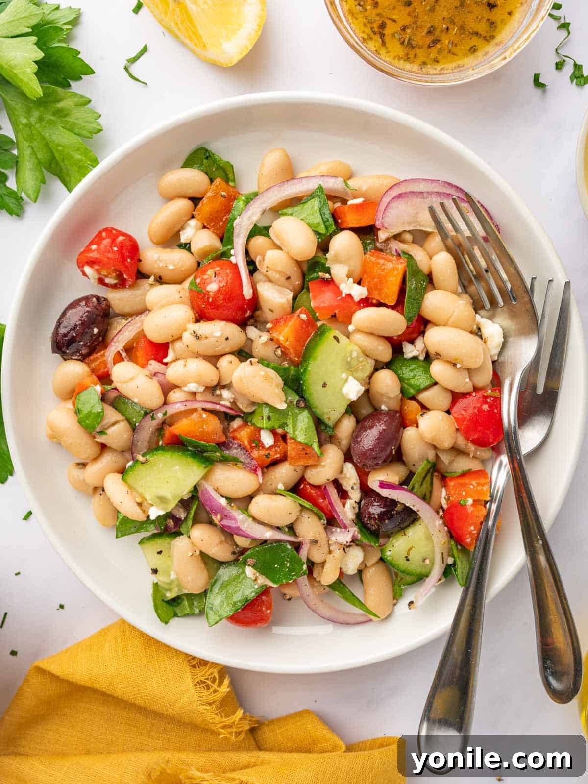A bowl of Greek Bean Salad with two forks resting on the side. The finished salad, ready to be eaten, with forks suggesting its immediate enjoyment.