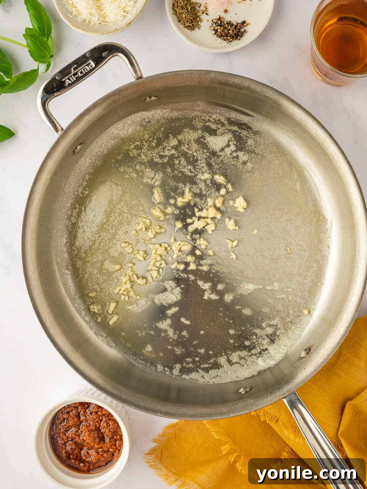 Minced garlic is being sautéed in a pan with melted butter.