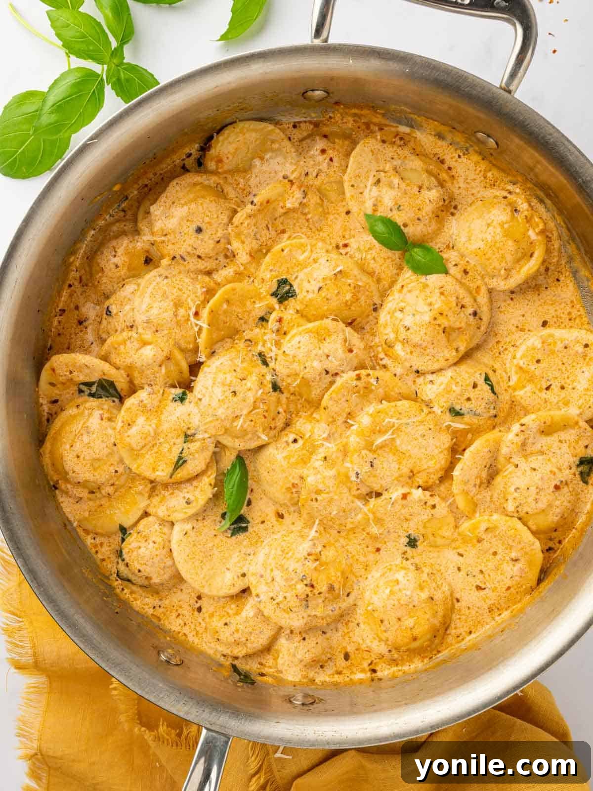 A large skillet filled with creamy cheese ravioli pasta, ready to be served.