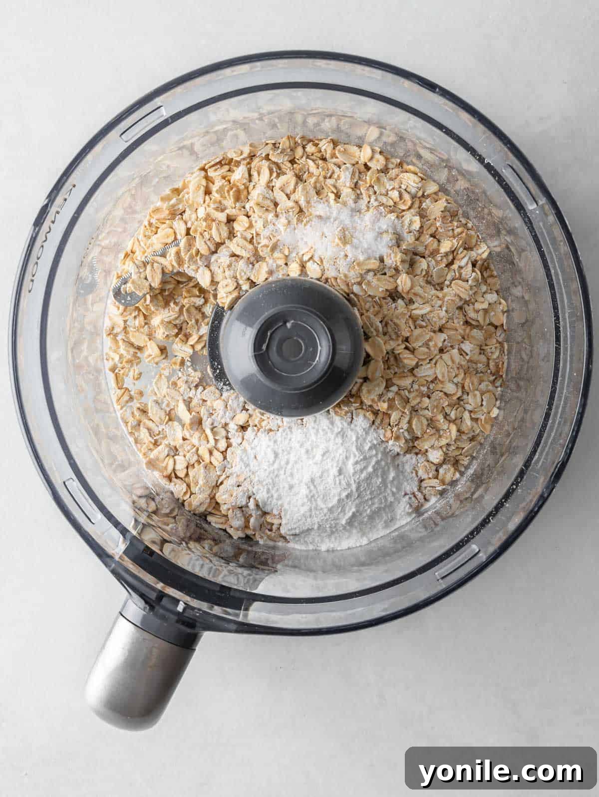 Oatmeal, protein powder, and cocoa powder being blended in a food processor to create the pancake flour.