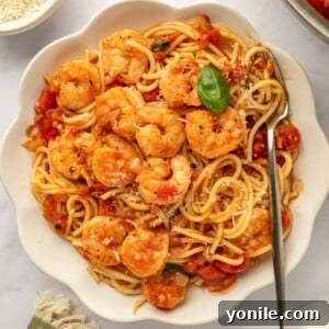 A bowl of pasta topped with sauteed shrimp.