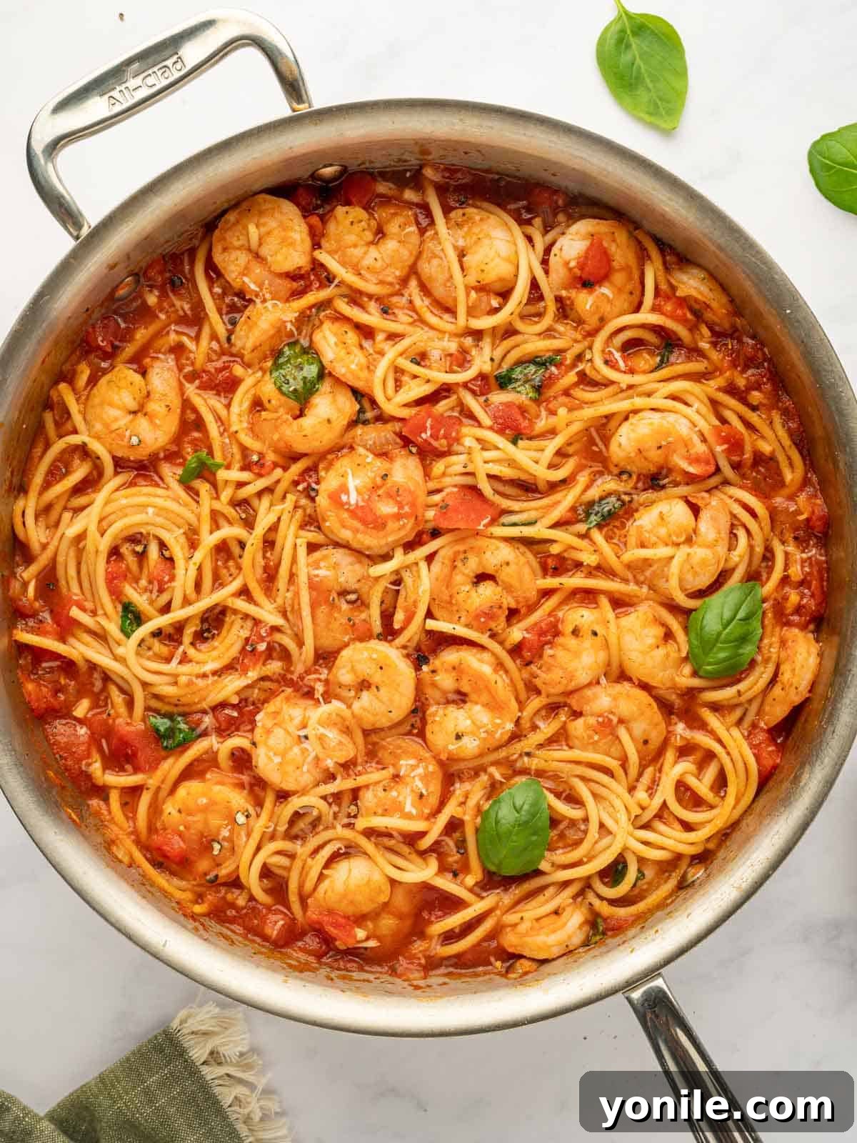 Prawn Pasta Perfection 10 A close-up of shrimp spaghetti tossed in sauce, garnished with fresh basil in a skillet.