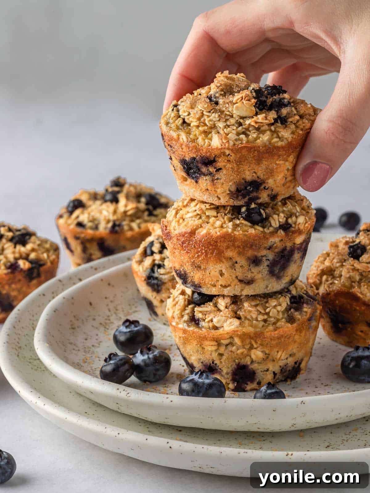 A hand places a blueberry cup on a stack of other oatmeal cups.