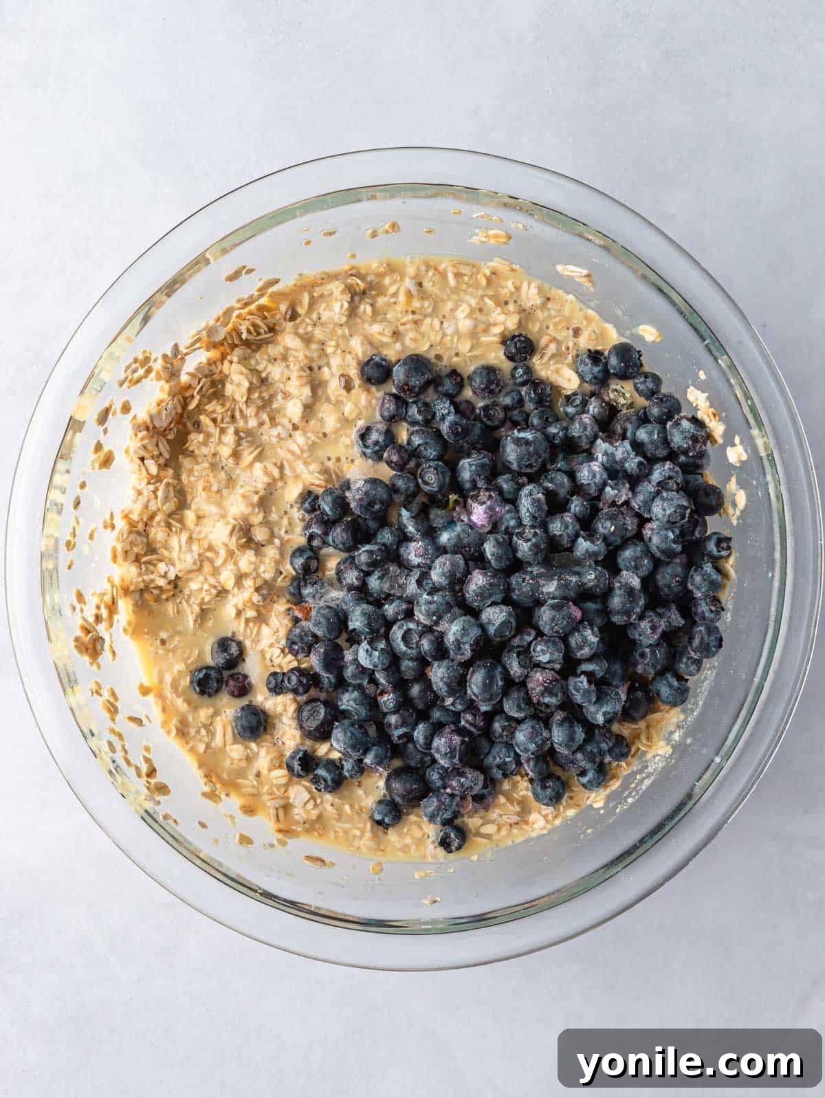 Making blueberry cups process, showing blueberries added to the mixture.