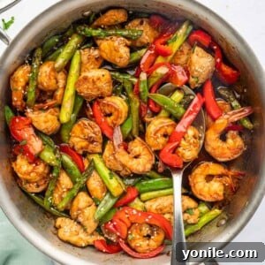 A spoon serves stir fry with chicken and shrimp.