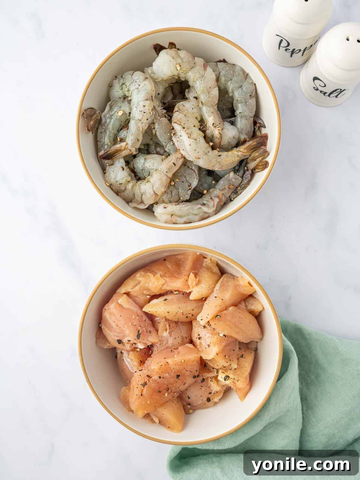 Sizzling Surf and Turf Stir-Fry 4 Raw chicken breast pieces and peeled, deveined shrimp laid out on a cutting board, seasoned with salt and pepper, ready for cooking.