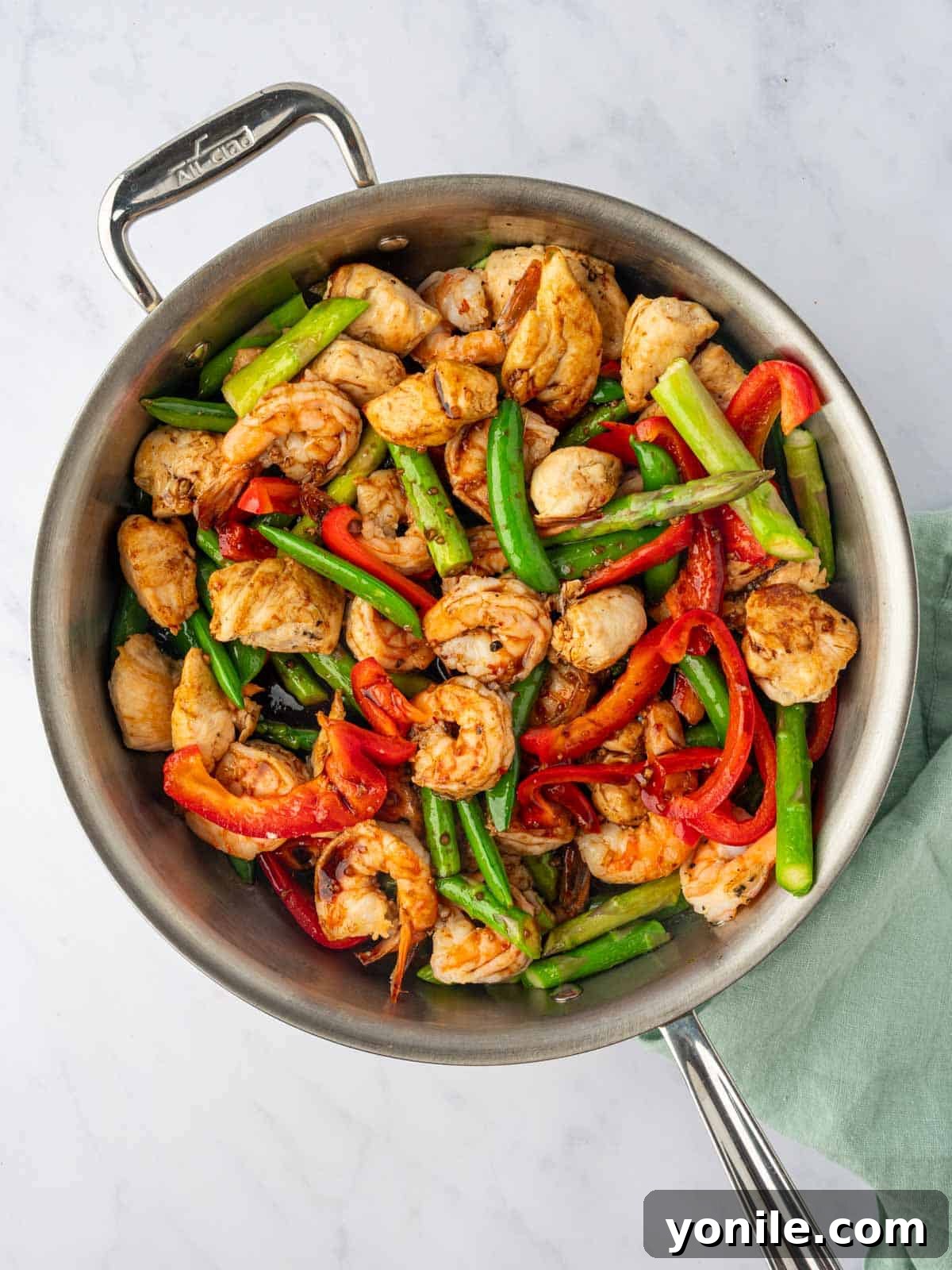 Sizzling Surf and Turf Stir-Fry 8 A colorful chicken and shrimp stir fry in a large skillet, with cooked chicken, shrimp, and vibrant vegetables coated in a glossy, rich sauce, ready to be served.