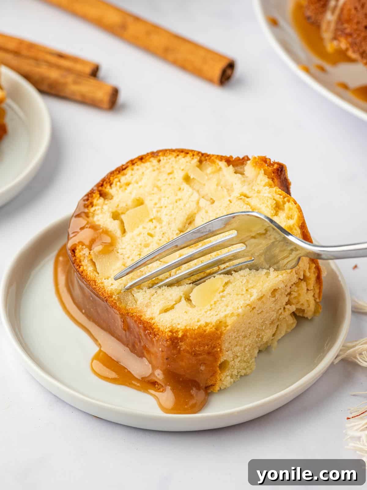 A fork slices into a piece of pear cake.