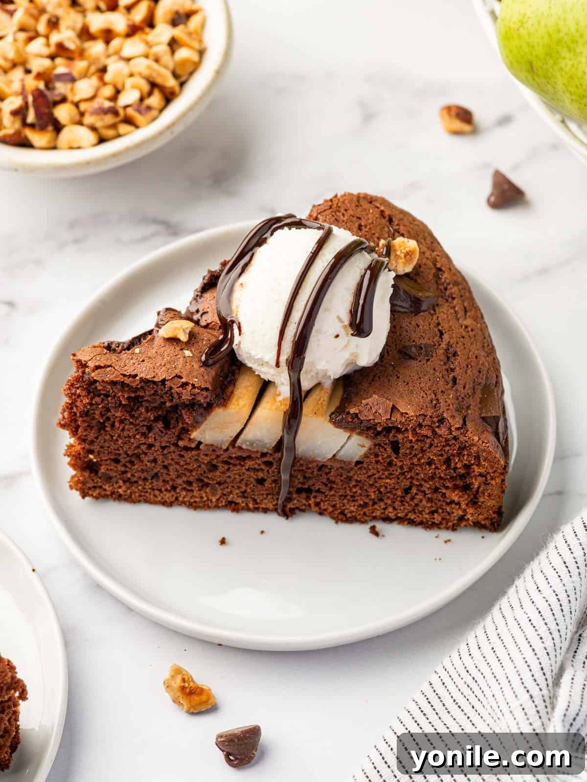 A delectable slice of pear cake, adorned with a scoop of vanilla ice cream and a chocolate drizzle.