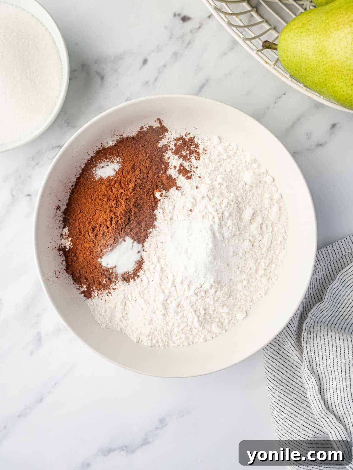 Dry ingredients for chocolate pear cake, including flour, cocoa, and leavening agents.