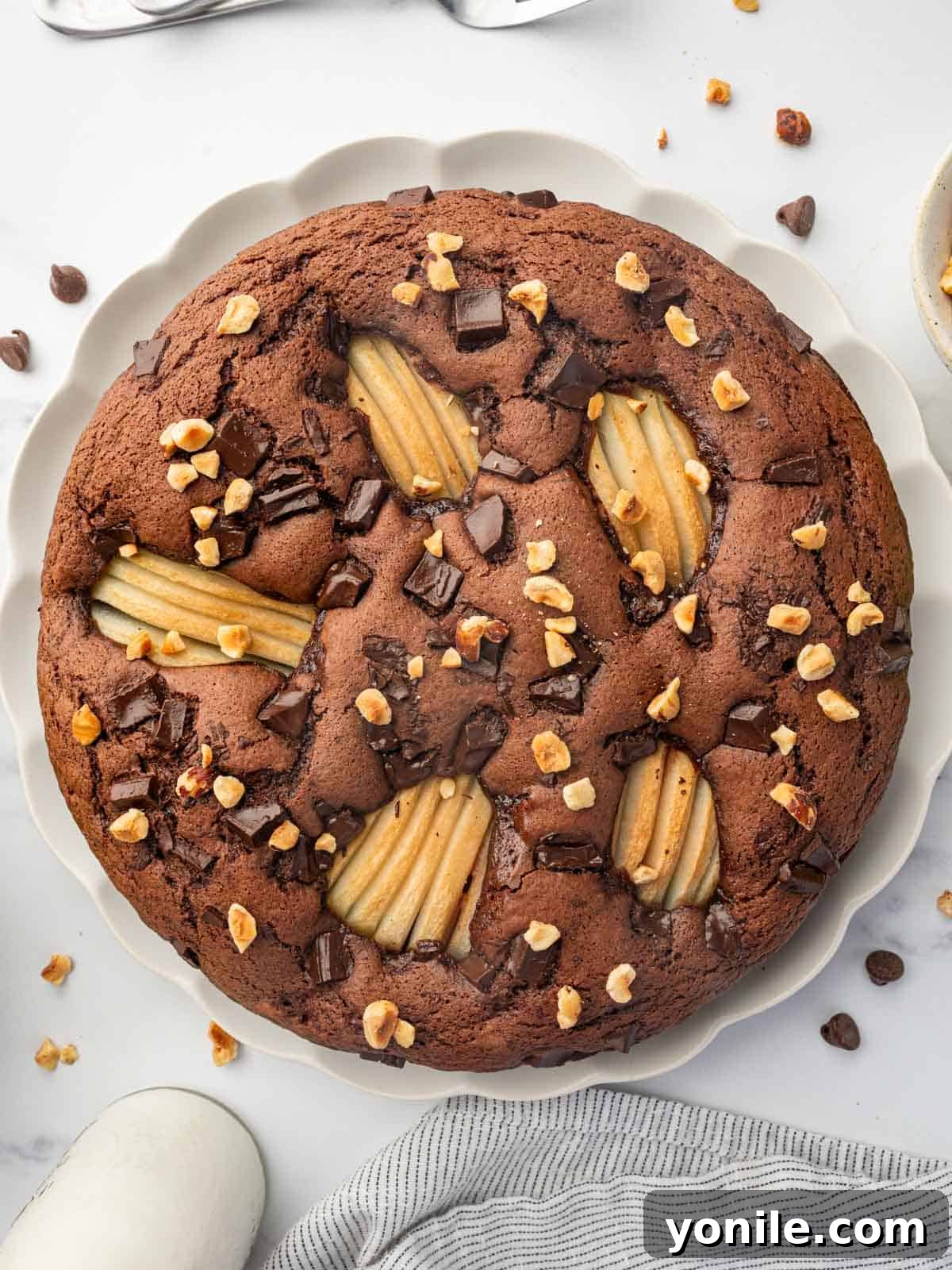 Top view of a beautifully baked chocolate pear cake, garnished with hazelnuts.