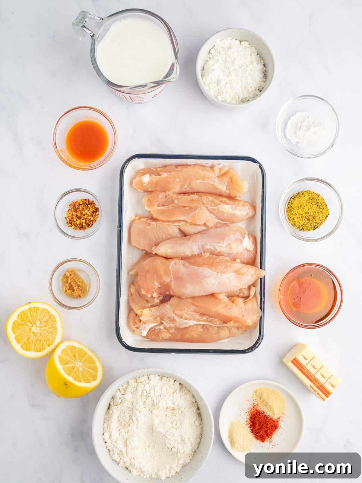Zesty Lemon Pepper Chicken Tenders 3 Fresh ingredients laid out for making lemon pepper chicken strips, including chicken, lemons, buttermilk, flour, and spices.