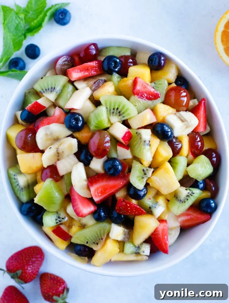 Fruit Salad Bowl A large white bowl filled with a colorful array of fresh, ripe fruit chunks, ready for dressing.