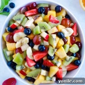 A generous bowl of colorful fruit salad with a light dressing, a perfect healthy dessert.