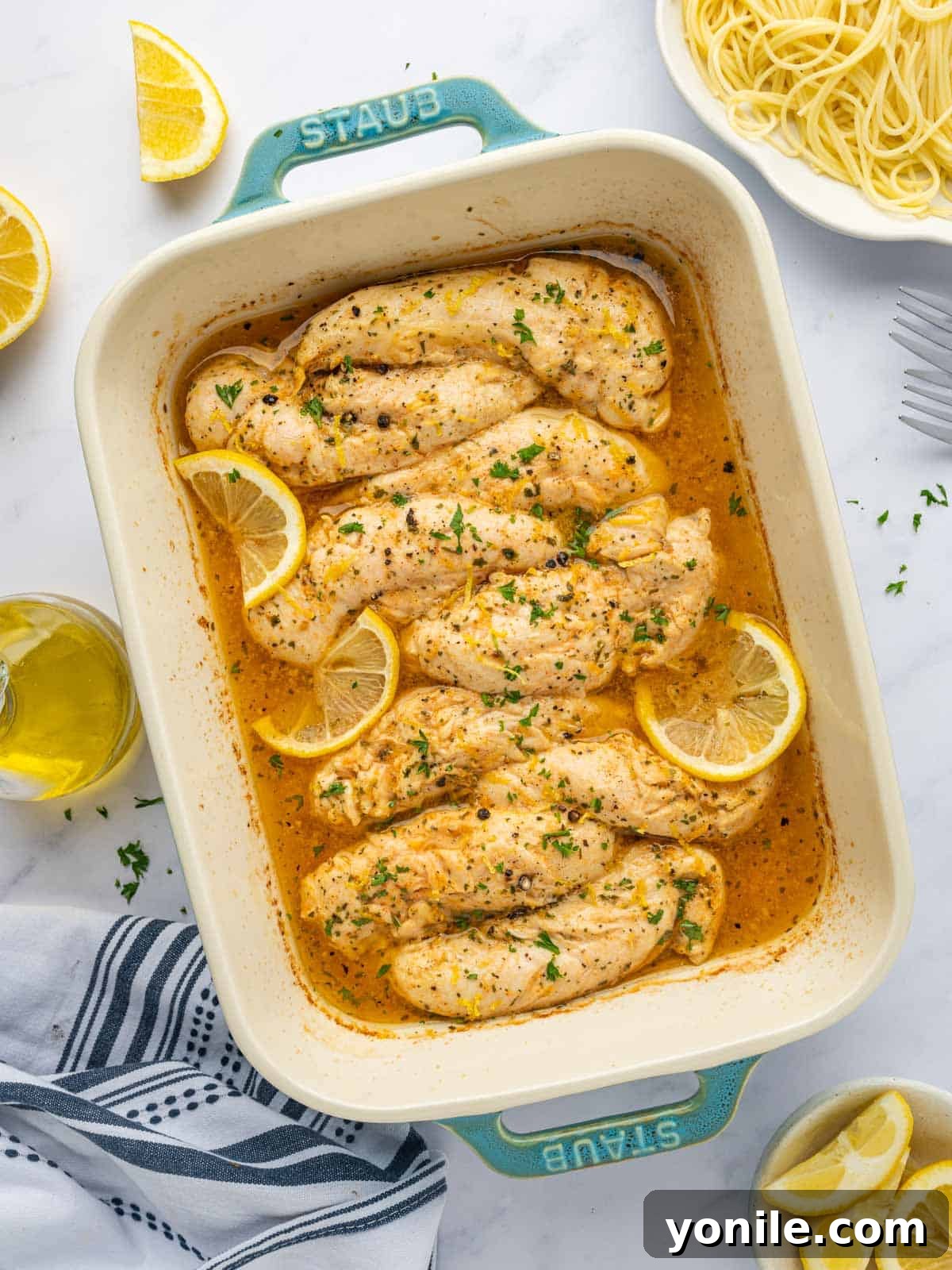 Baked lemon pepper chicken in a casserole dish, garnished with fresh herbs.