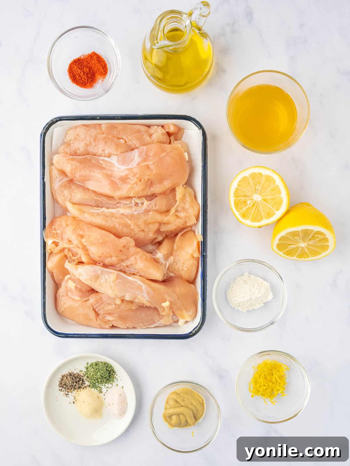 Ingredients needed for lemon pepper chicken tenders, including lemon, garlic, cilantro, and chicken.