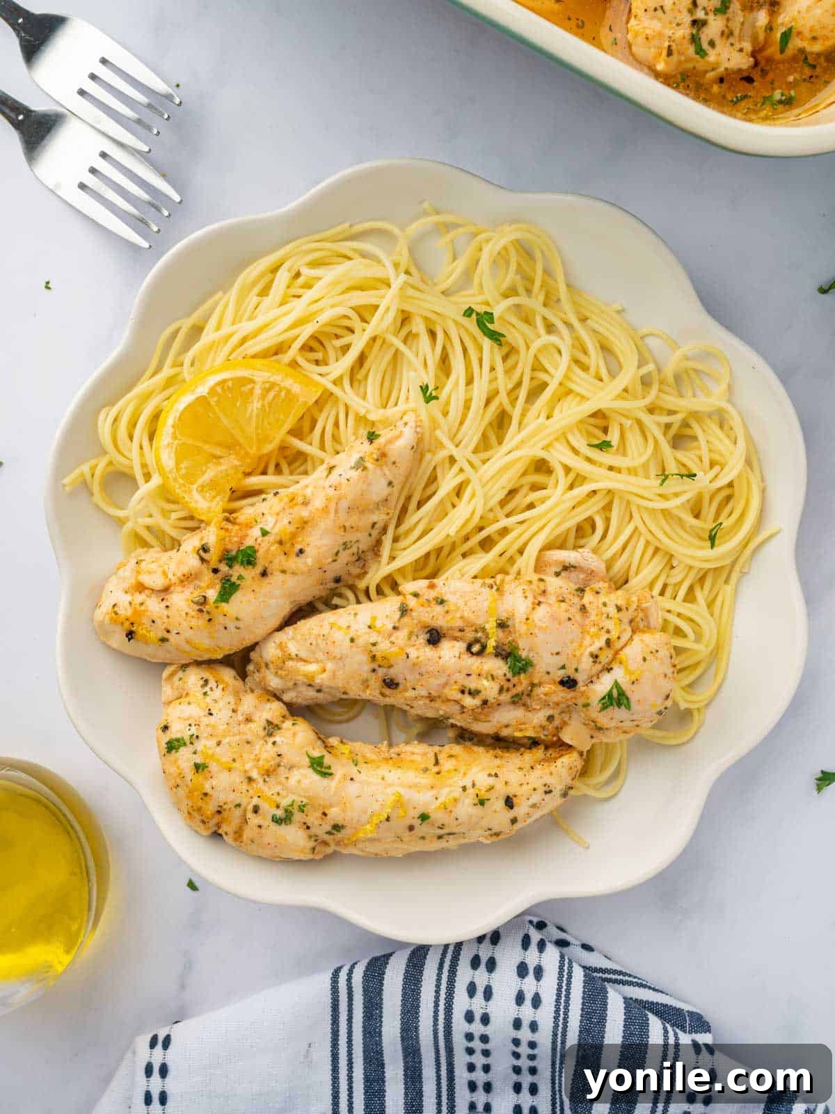 Lemon pepper chicken with pasta on a plate, garnished with fresh herbs.