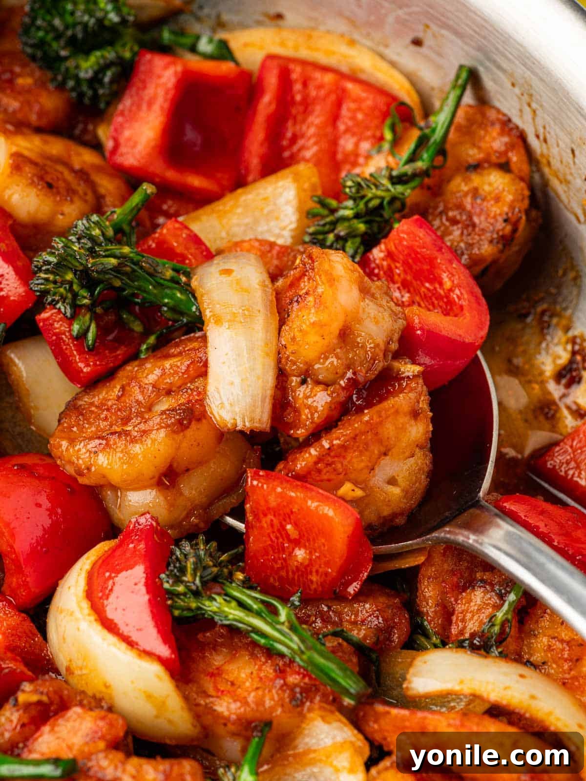 Panda Express Wok-Fired Sizzling Shrimp 10 A serving spoon lifting a portion of Sizzling Shrimp and vegetables from a skillet, showcasing the rich sauce.